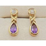 A pair of modern design 9ct gold amethyst and diamond set drop style earrings. Each set with a small