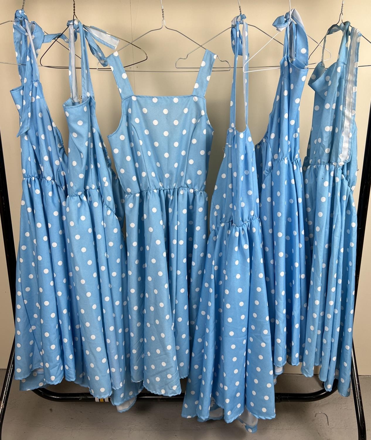 6 matching blue polka dot dresses, 5 of halter neck design.