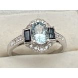 A 9ct white gold Art Deco style dress ring set with aquamarine, sapphires and diamonds. A central