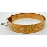 A vintage 9ct rolled gold hinged bangle engraved with foliate and scroll design. Complete with