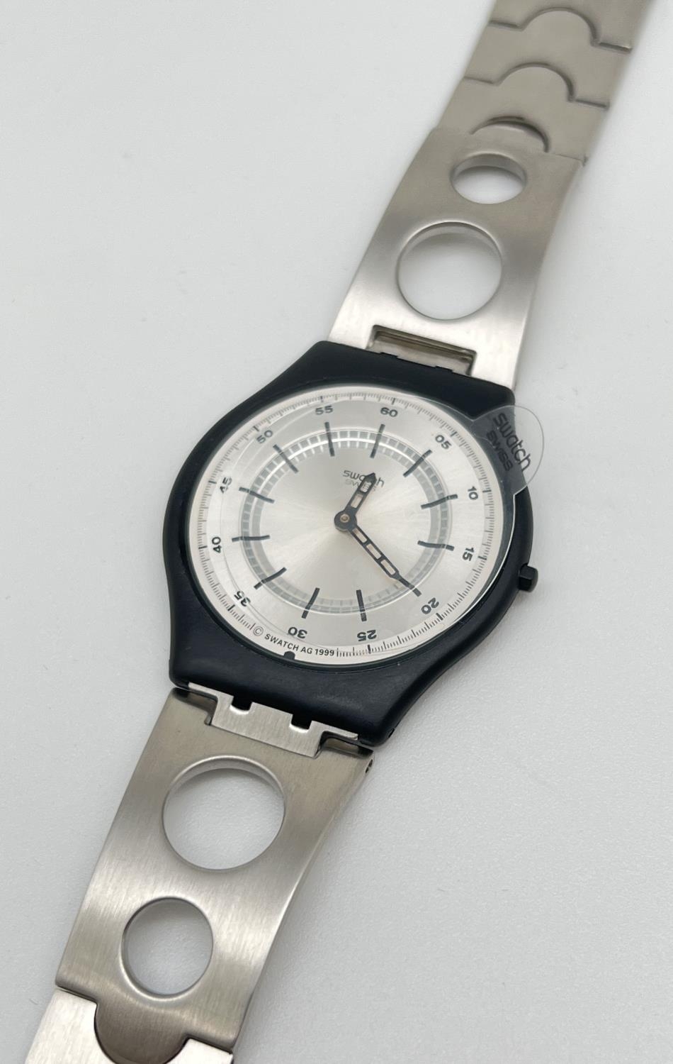 An AG 1999 Swatch watch with black plastic case and stainless steel strap. With original box and