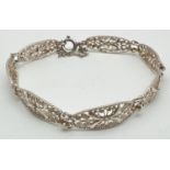 A vintage silver bracelet with 7 floral design filigree panels, spring clasp & safety chain.