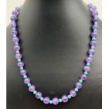 A 17" beaded necklace of alternating amethyst and turquoise beads. With a decorative flower design