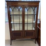 An Edwardian inlaid display cabinet with double doors and fabric lined interior shelving and back.