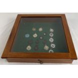 A glass topped small table top display cabinet containing a collection of vintage sports medals.