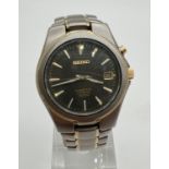 A Seiko 5M62-OAMO kinetic Titanium wristwatch with black face and gold tone hands. Hour markers with