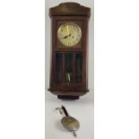 A vintage dark oak cased wall hanging, swinging pendulum clock. Complete with key & pendulum. With