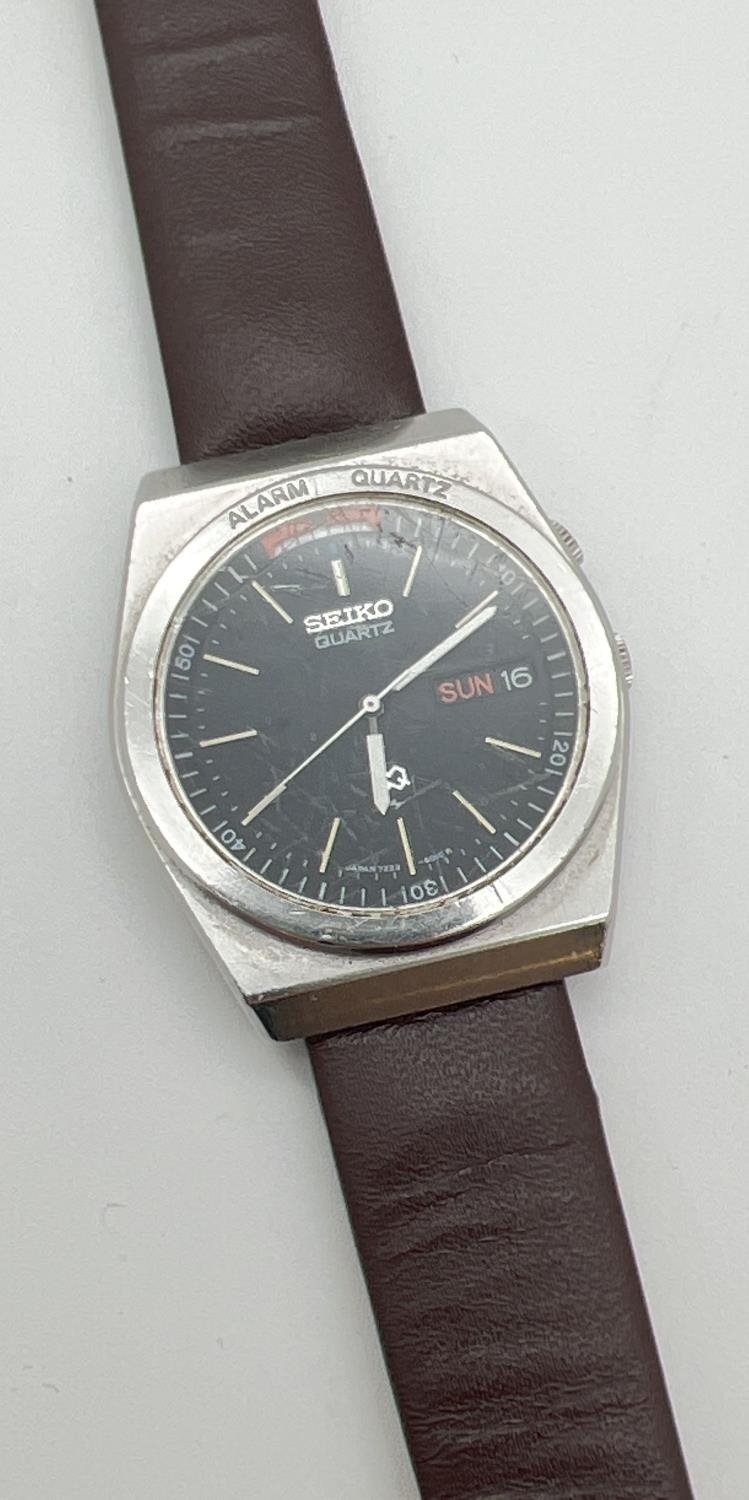 A vintage 072700 Seiko wristwatch with brown leather strap. Black face with luminous hour markers