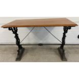 A vintage wooden topped table with cast iron base. Painted black cast iron decorative legs with