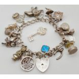 A vintage charm bracelet with padlock clasp and safety chain. With 19 silver and white metal
