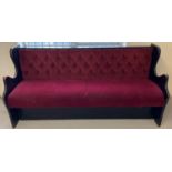 A vintage painted black wooden pub bench seat with button back red velour upholstery and shaped
