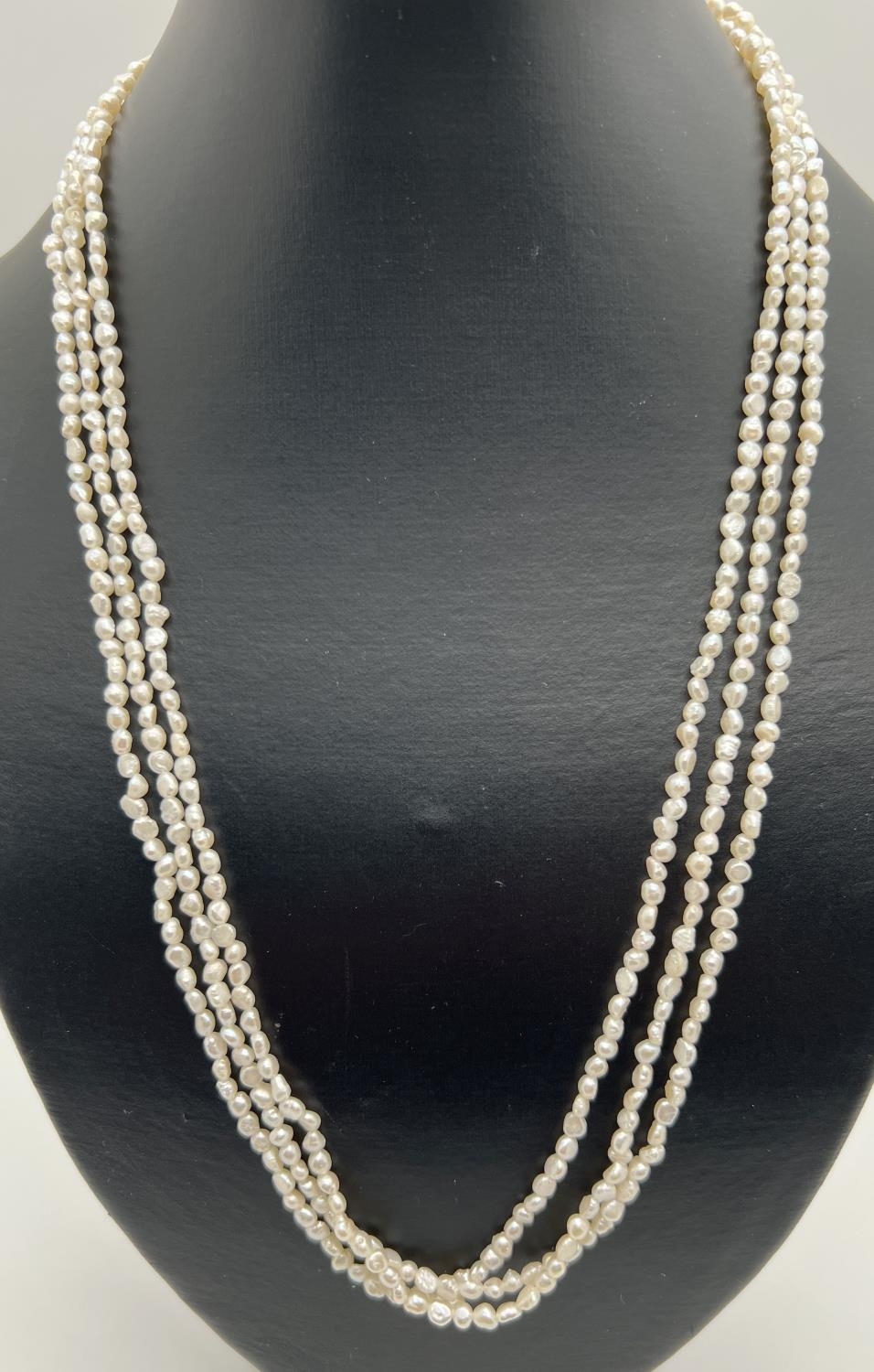 A 22 inch 3 strand small baroque pearl necklace with gold tone pierced work clasp.