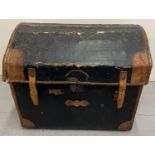 A Victorian dome topped wicker basket trunk with brown leather corners, handles and binding. With