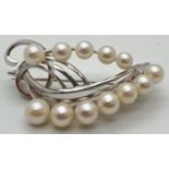 A silver and pearl floral design vintage brooch. Set with 12 graduating size white pearls. Marked
