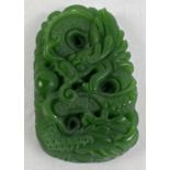 A carved jade flat backed roundel featuring a dragon. Approx. 5.5cm x 3.5cm.