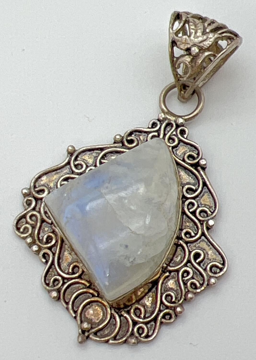 An ethnic design silver and moonstone pendant with scroll detailed mount and floral pierced work