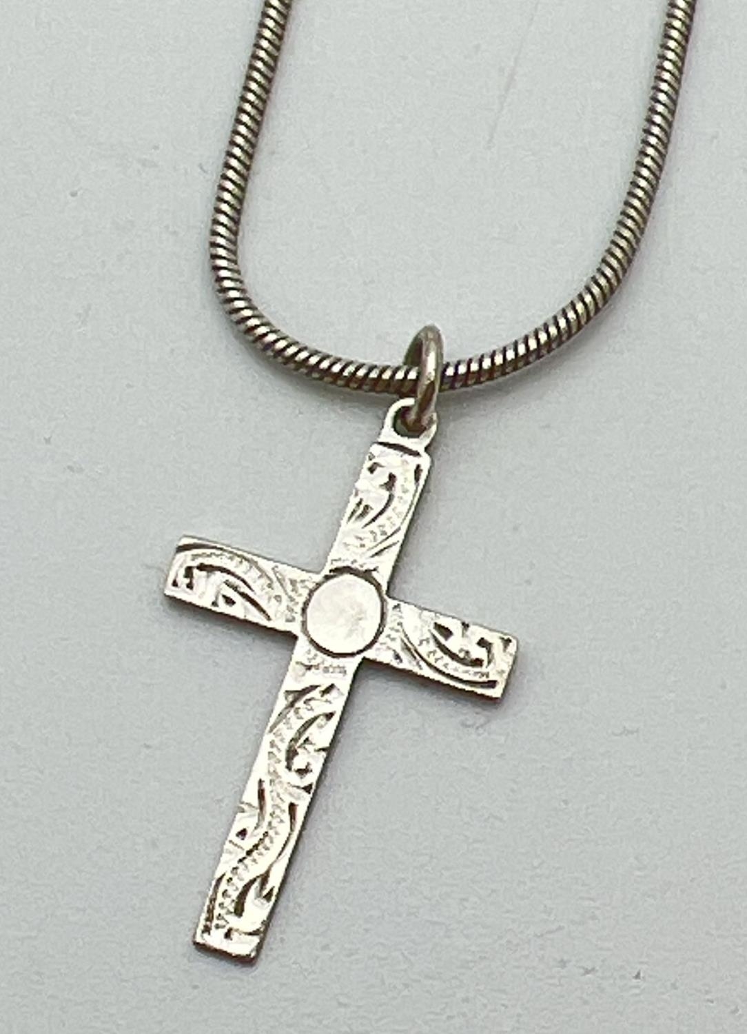 A vintage silver cross pendant with floral decoration to front on an 18" snake chain with lobster