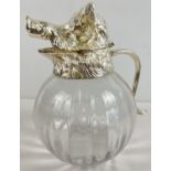 A large heavy bulbous glass claret jug with silver plated hinged lid in the form of a boars head.