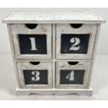 A small modern 4 drawer chest, painted white, with numbered draws. Approx. 26.5cm tall x 26.5cm