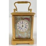 A miniature brass cased carriage clock with hand painted porcelain panels. Bevel edged glass, gilt