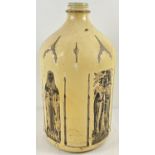 A large vintage glass bottle painted cream and decorated with Gothic design brass rubbing prints.