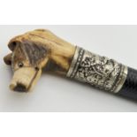 An antique riding crop with carved antler horn handle in the form of a dogs head. Set with glass