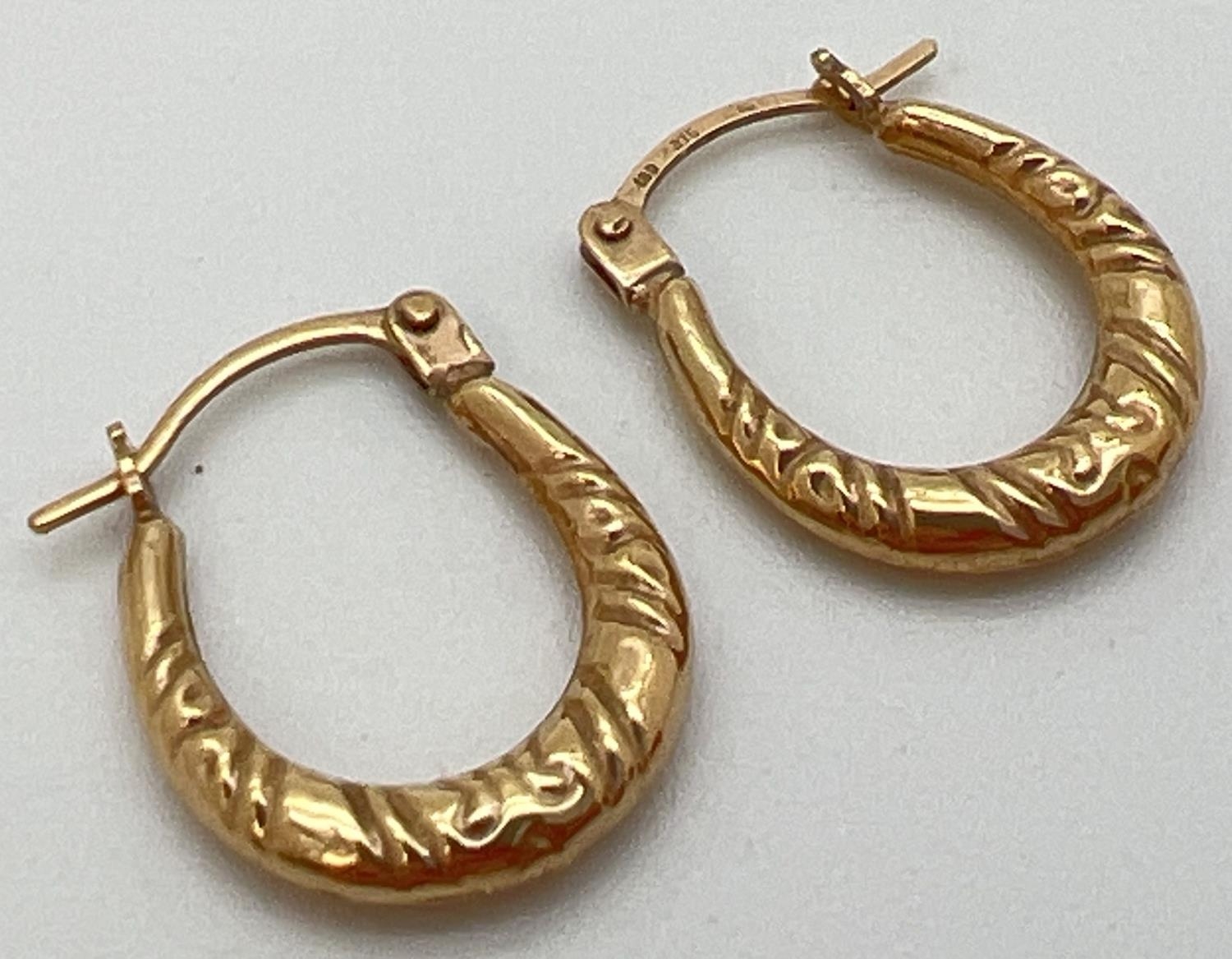 A pair of 9ct gold creole style earrings with hinged posts. Approx. 1.5cm drops and 0.5g total