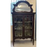 An ornate highly carved Victorian walnut display cabinet with mirror back panel. Raised on tapered