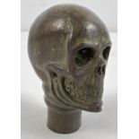 A hollow bronze walking stick handle in the form of a skull. Approx. 7cm long.