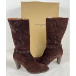 A boxed pair of heeled chocolate brown suede calf length boots with leather cross decoration, by