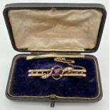An Edwardian 9ct gold double bar brooch set with a ruby and seed pearls, in original box. A