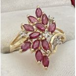 A 14ct gold ruby and diamond set dress ring in a flower design mount. 12 marquise cut small rubies