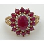 A 9ct gold cluster style ruby and diamond dress ring with scroll detail to shoulders. Central oval