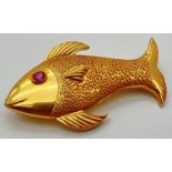 A 22ct gold brooch in the shape of a fish set with oval cut ruby eye. Patterned detail to body