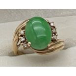 A vintage 14ct gold jade and diamond set dress ring. A twist design mount set with an oval