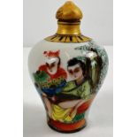 A small Chinese ceramic snuff bottle with painted erotic scene. Gilt painted stopper and top rim.