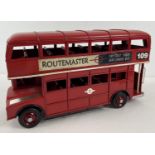 A modern tin plate Routemaster double decker bus, painted red, with decals to sides. Approx. 30 x