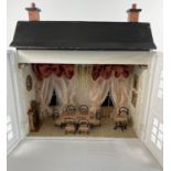 A vintage wooden dolls house furnished as a made up dining room in pink, cream and gold. To
