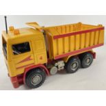 A 1:16th scale hard plastic yellow and red 6 wheel tripper truck, by Bruder.