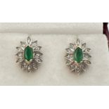 A pair of 9ct gold emerald and diamond set floral style stud earrings. Each earring set with a