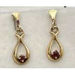 A pair of vintage drop style earrings set with a small round cut garnet. Complete with butterfly