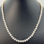 An 18" knotted white pearl necklace with pierced work 10K gold fish hook clasp.