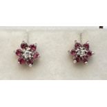 A pair of flower design ruby and diamond set stud earrings. Central round cut diamond surrounded