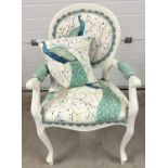 A modern bedroom armchair, painted white, with peacock design upholstery and matching cushion.