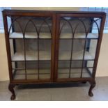 A vintage dark wood 2 door glass display cabinet raised on 4 ball & claw footed legs. Fabric lined