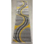 A modern "Ochre" runner rug in grey and mustard yellow colours with swirl design. Approx. 228cm x