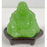 A small carved green jade sitting Buddha figure on a small wooden stand. Figure approx. 5.5cm tall.