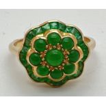 A 9ct gold emerald and jade dress ring in a fluted edge flower design by Luke Stockley, London.