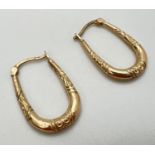 A pair of drop hoop style earrings with embossed scroll decoration. Marked 375 to posts. Total