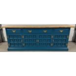 A modern solid wood sideboard with natural wood top and teal painted base. 4 cupboards to base